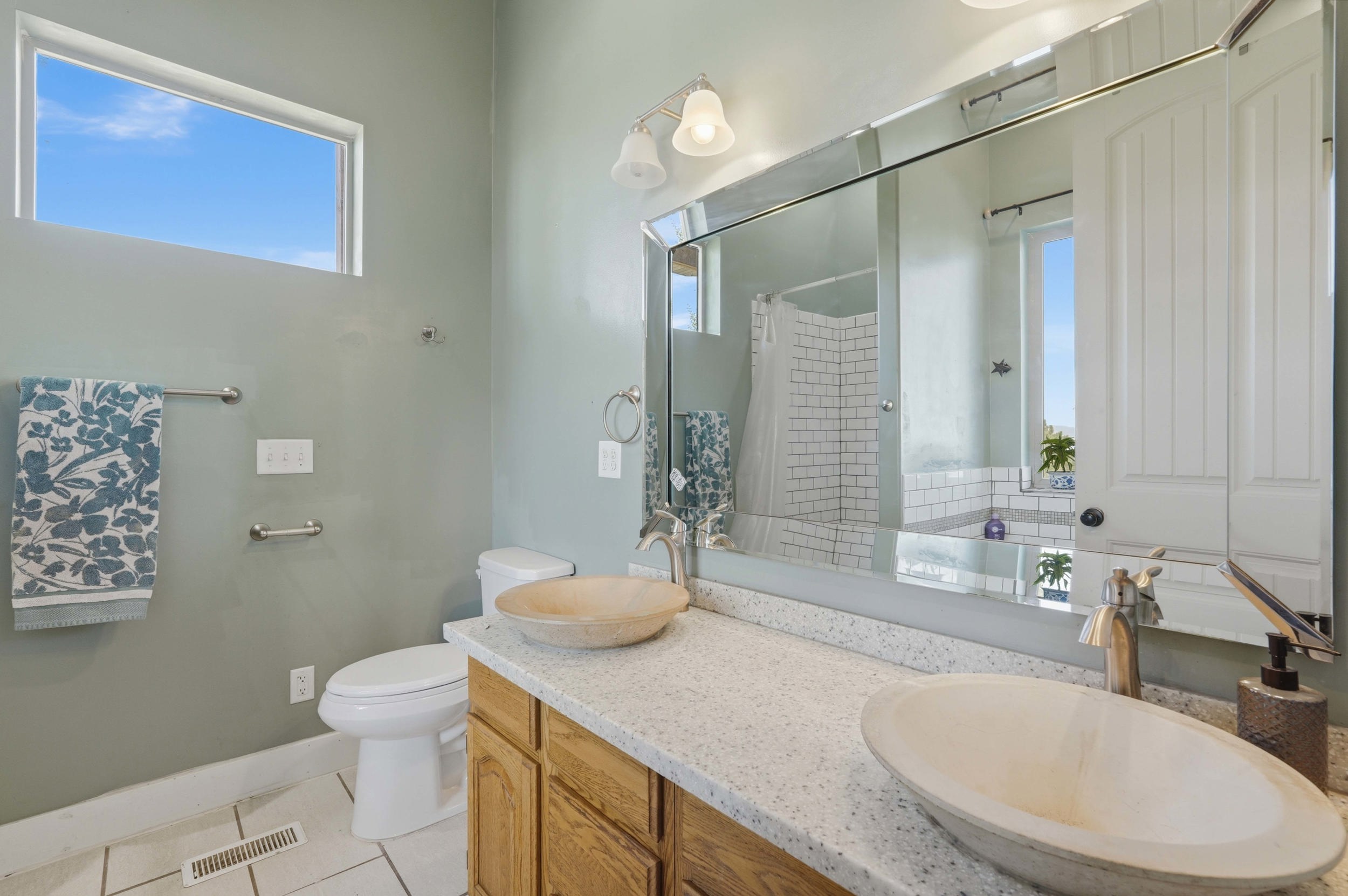 Bathroom featuring a dual vanity with vessel sinks, speckled countertops, and wood-finish cabinetry