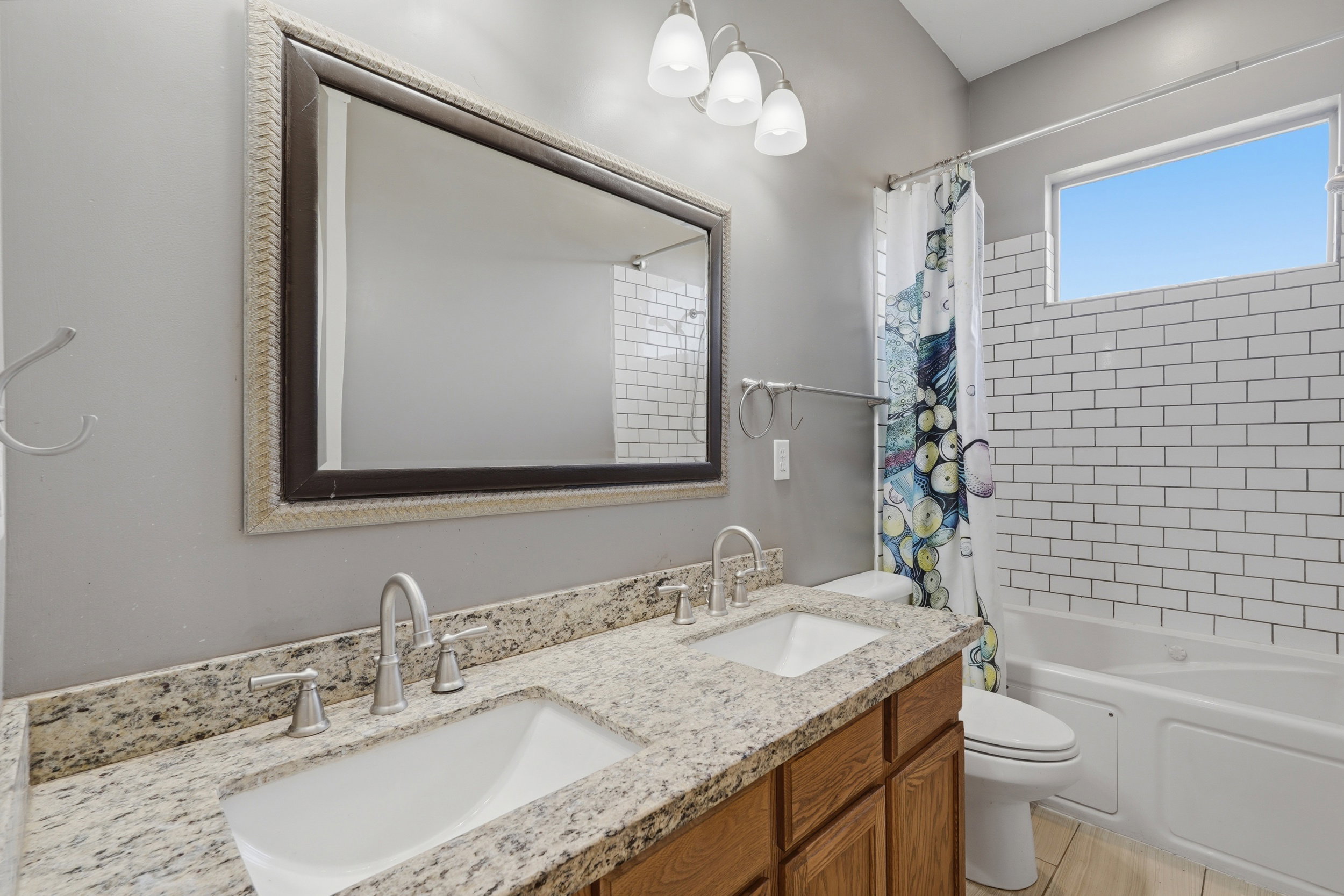 Bathroom featuring a dual vanity with granite-finish countertop, undermount sinks, and brushed nickel fixtures