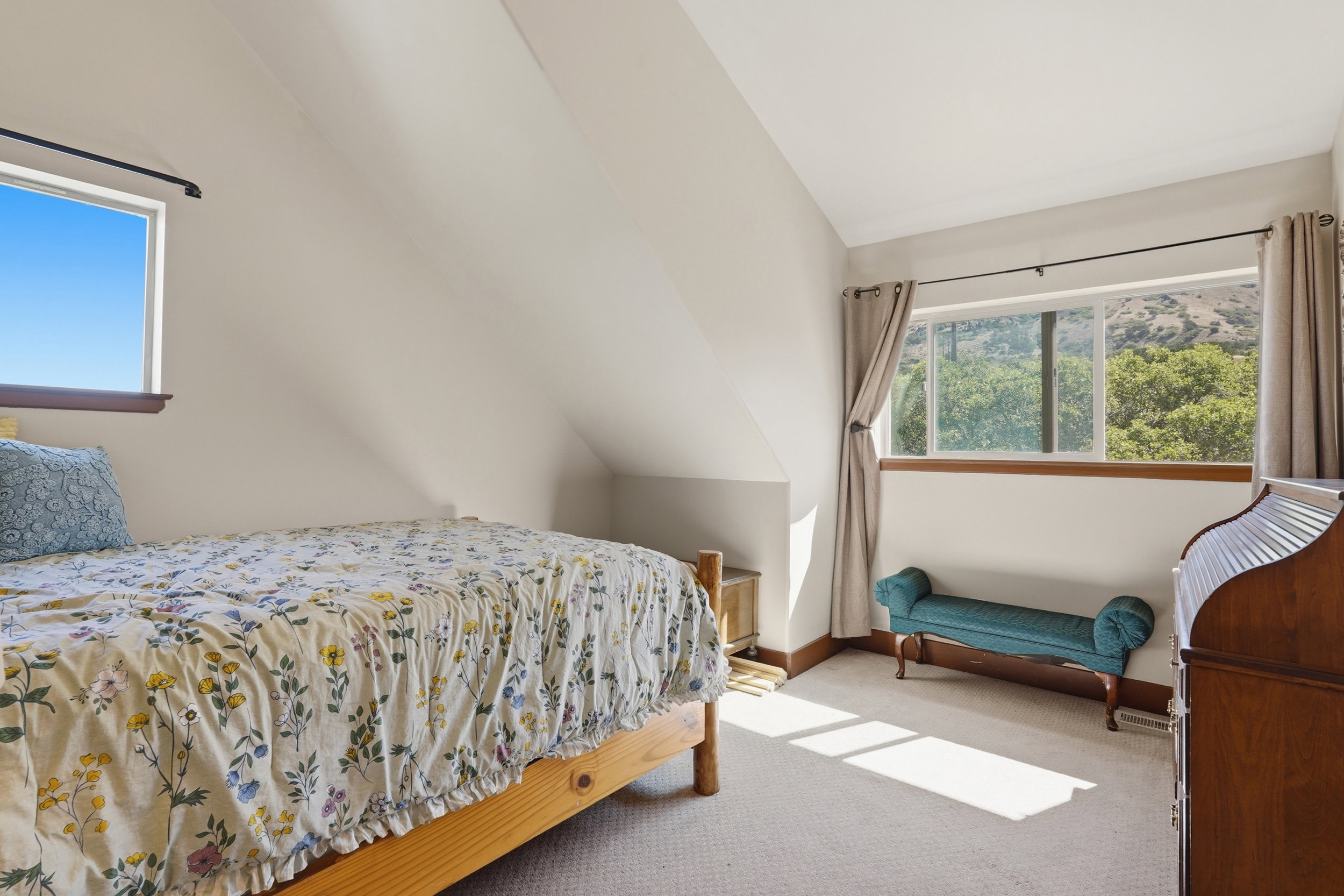 Carpeted room with a distinctive sloped ceiling and multiple windows