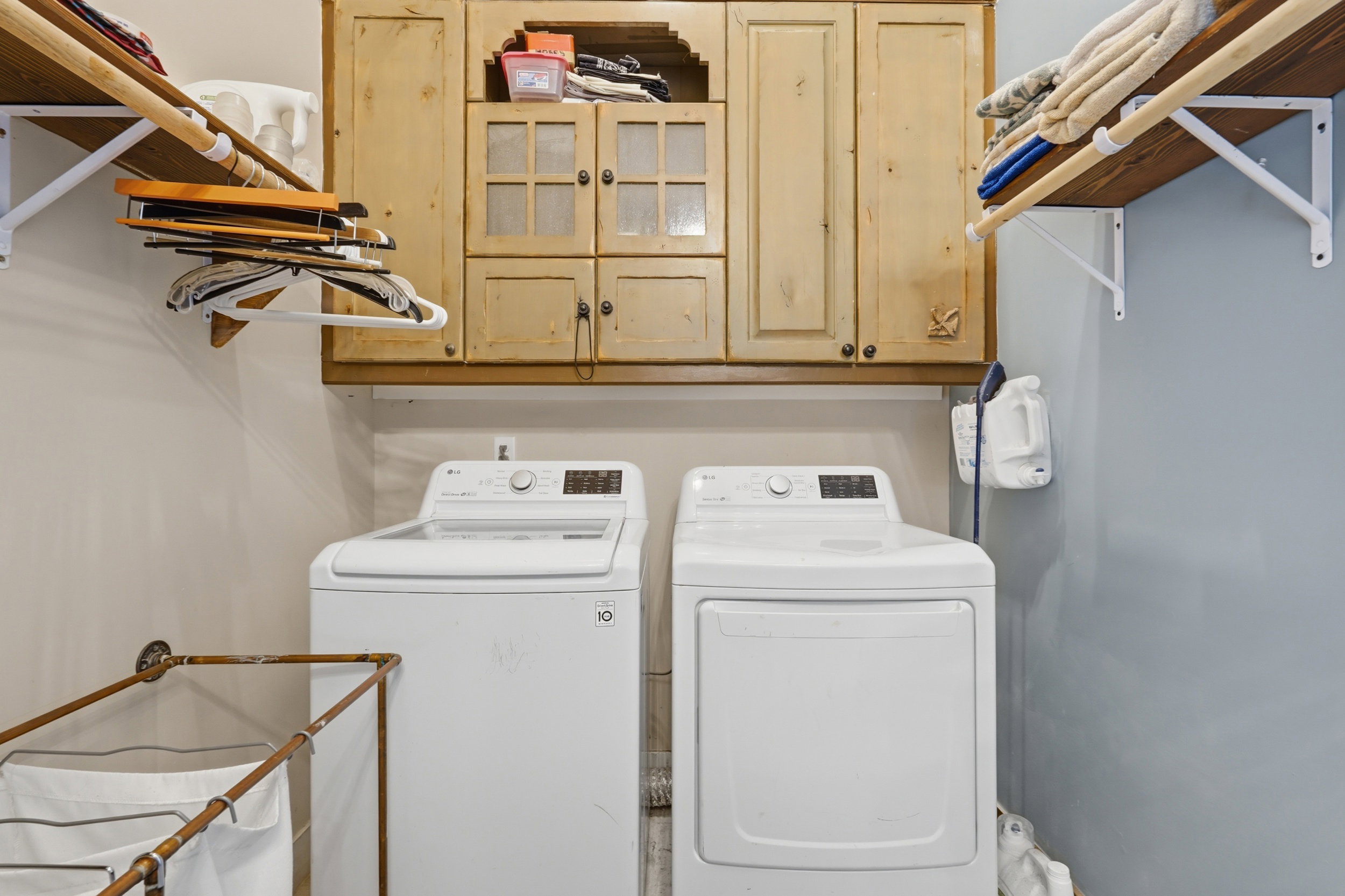 Laundry area featuring light wood cabinetry, shelving with integrated hanging rods, a modern washing machine, and a dryer