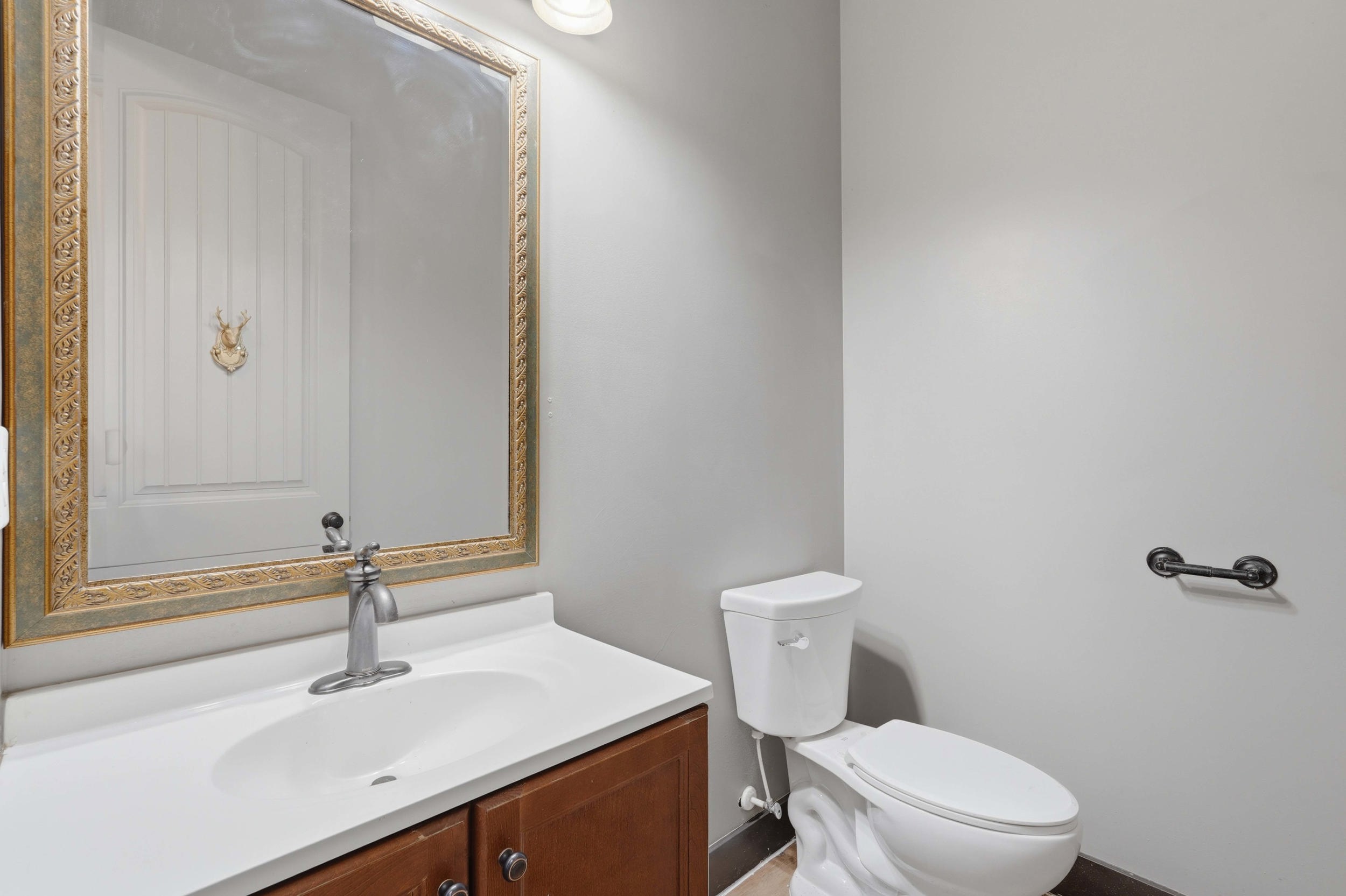 Bathroom vanity featuring a white sink basin, brushed nickel faucet, and a brown wood-finish cabinet