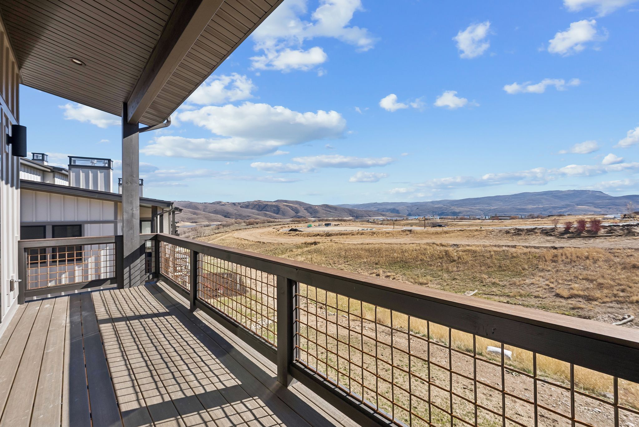 Expansive outdoor deck featuring wood-finish flooring and a contemporary metal grid railing
