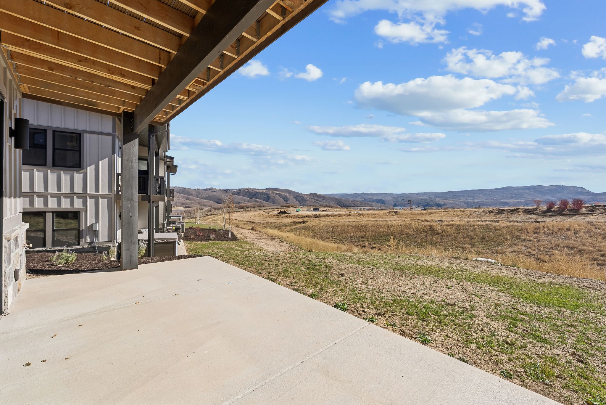 Expansive concrete patio with a wood-plank soffit and exposed beams, offering open-air outdoor space