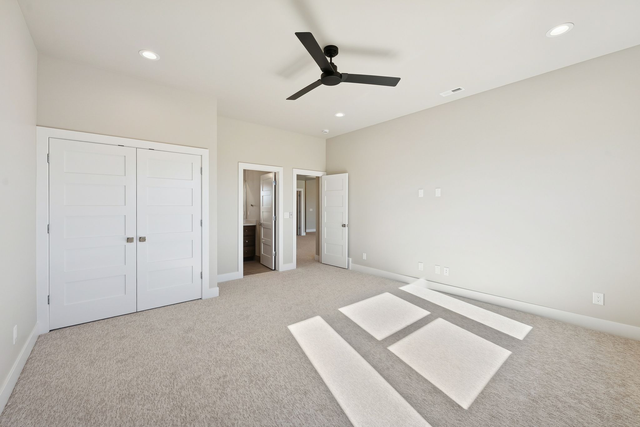 Spacious room featuring neutral carpeting, recessed lighting, and a modern black ceiling fan