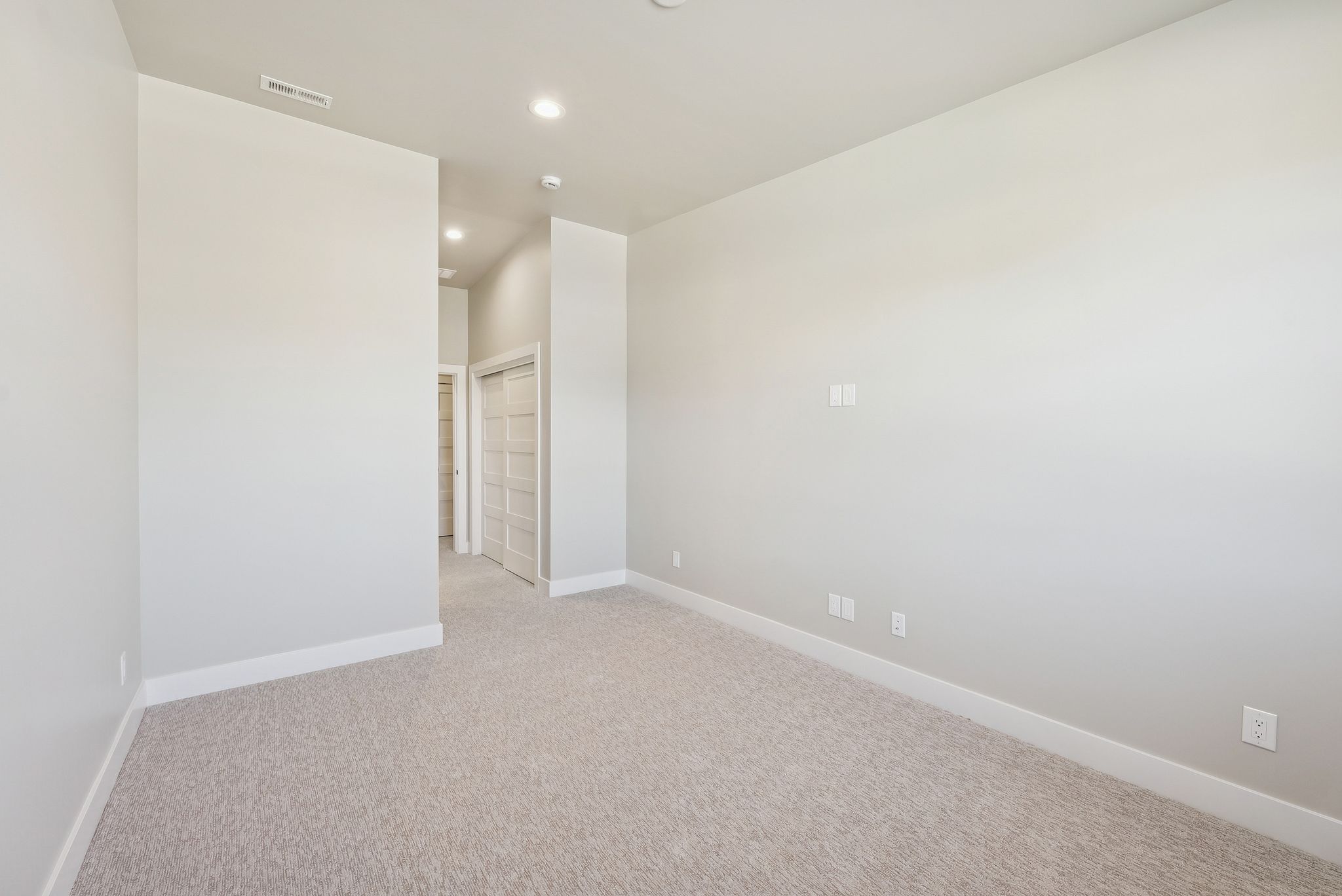 Spacious room featuring light-toned carpeting, white baseboards, and neutral wall paint