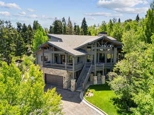 Mountain modern residence featuring extensive stone accents, a multi-level deck, and a prominent chimney