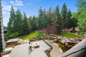 Expansive outdoor living area featuring a stone patio, built-in fire pit, and integrated hot tub