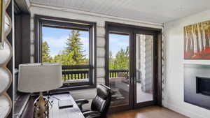 Spacious room featuring a fireplace with a brushed metal surround, wood-finish flooring, and a white planked ceiling