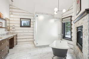 Freestanding clawfoot tub and a glass-enclosed shower complement the white log walls