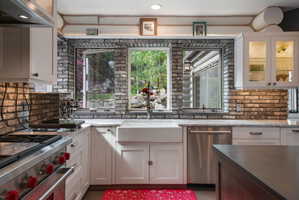 Kitchen featuring white cabinetry, brick backsplash, and light-toned countertops