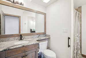 Bathroom vanity featuring a wood-finish cabinet, granite-style countertop, and vessel sink with a matte black faucet