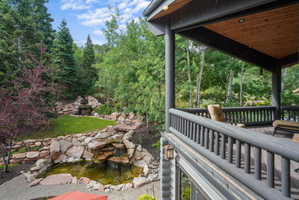 Multi-level outdoor living space featuring a wood deck, log-style railing, and natural wood ceiling