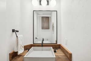 Powder room featuring a concrete vessel sink, matte black faucet, and a rustic wood countertop