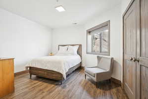 Room featuring wood-finish flooring, white walls, and a window with grey trim