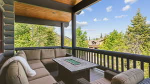 Covered balcony featuring stone-look siding, wood-finish ceiling, and dark-stained wood railings