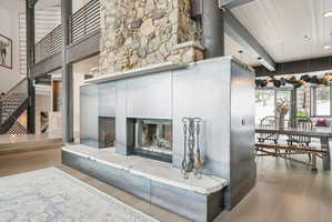 Central fireplace featuring a substantial stone chimney and a metal-clad surround