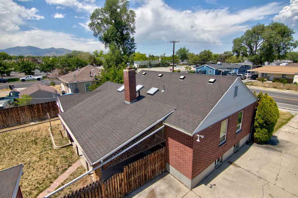 Gable-roof property featuring a brick exterior and a dark shingle roof