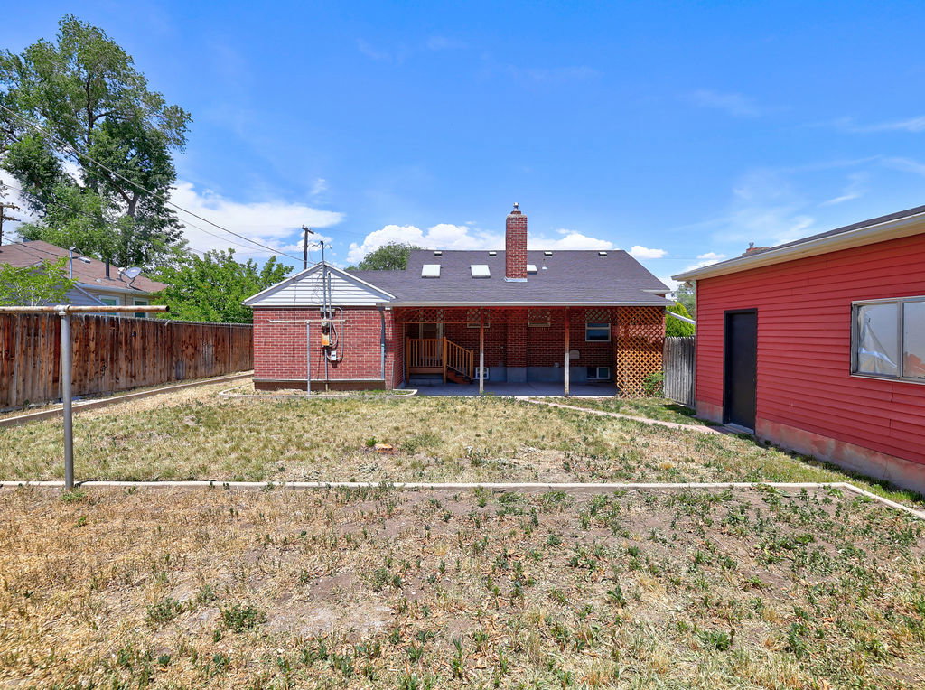Rear exterior featuring a covered patio, brick chimney, skylights, and a detached red outbuilding with windows