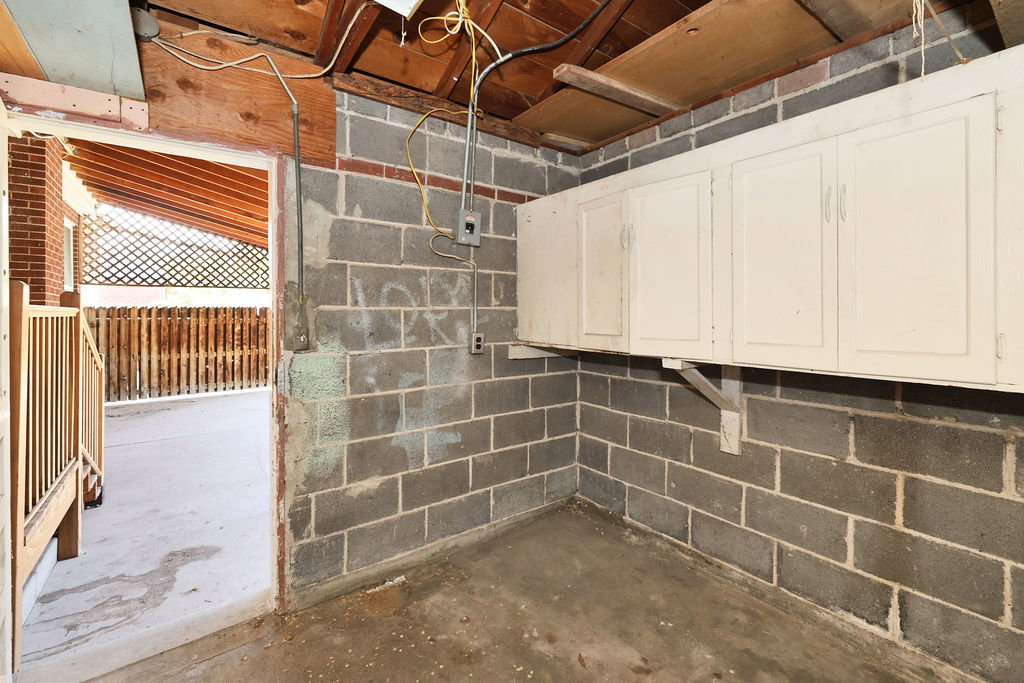 Cinder block room with concrete flooring and exposed wooden ceiling beams