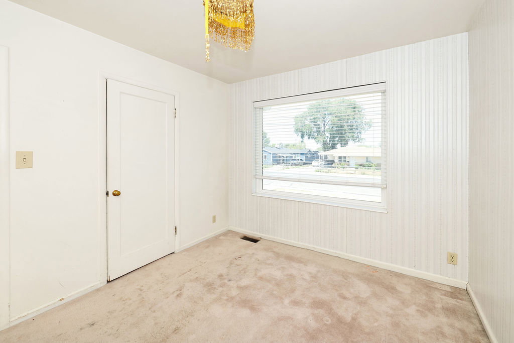 Room featuring light-colored carpet, a large window with blinds, and striped wallpaper on one wall