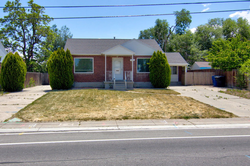 Brick exterior residence featuring a front lawn and paved driveways on either side
