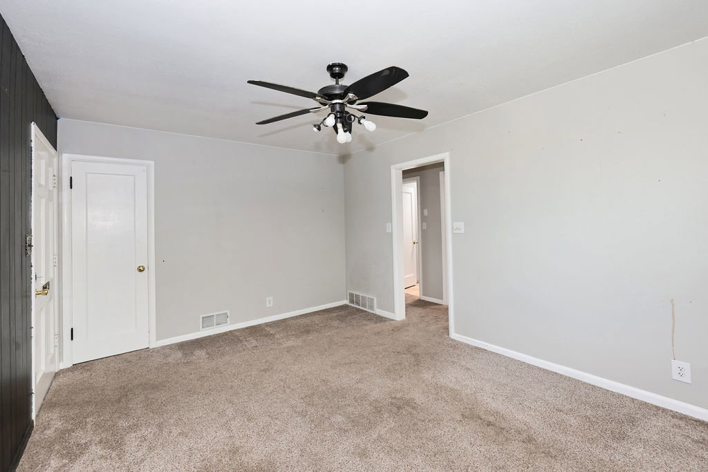 Spacious room with light gray painted walls and dark carpet flooring