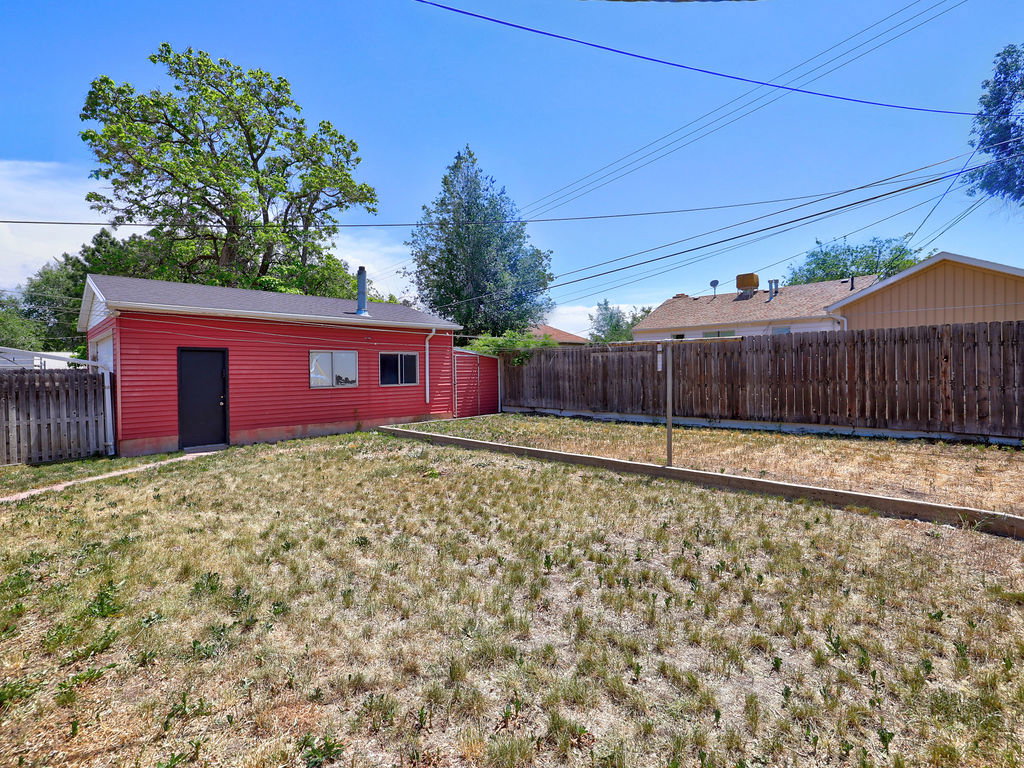 Detached red outbuilding with multiple windows and a side entry door