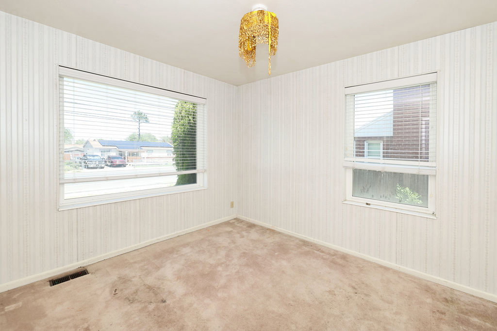 Room featuring two windows with horizontal blinds, textured wall coverings, and carpeted flooring