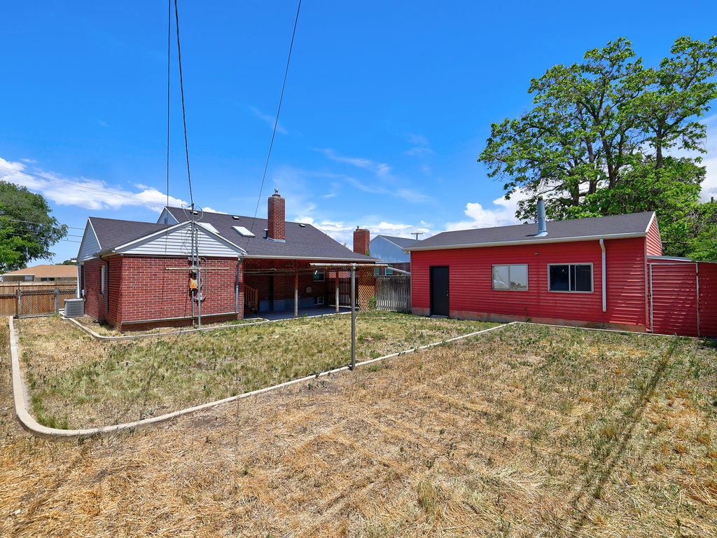 Expansive backyard featuring a red siding outbuilding with a dark entry door and multiple windows