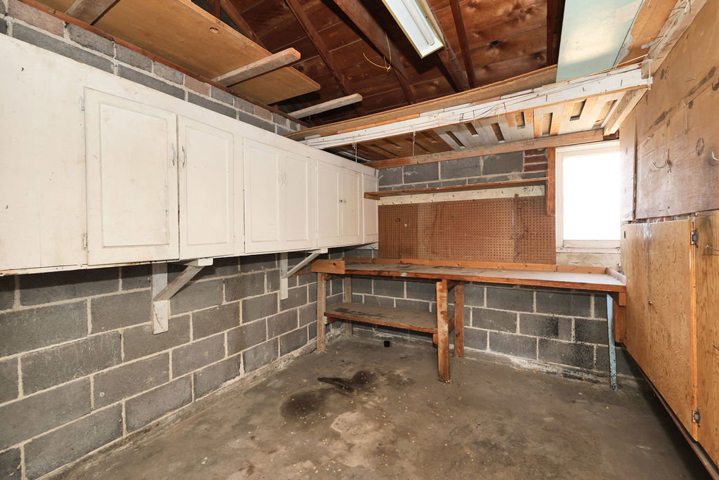 Utility space featuring concrete block walls and exposed wood beam ceiling