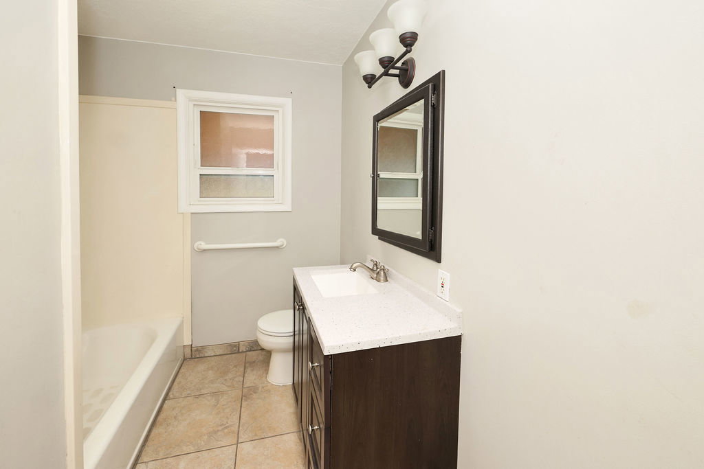 Bathroom featuring a dark wood-finish vanity with a light-toned countertop, an integrated sink, and brushed nickel fixtures
