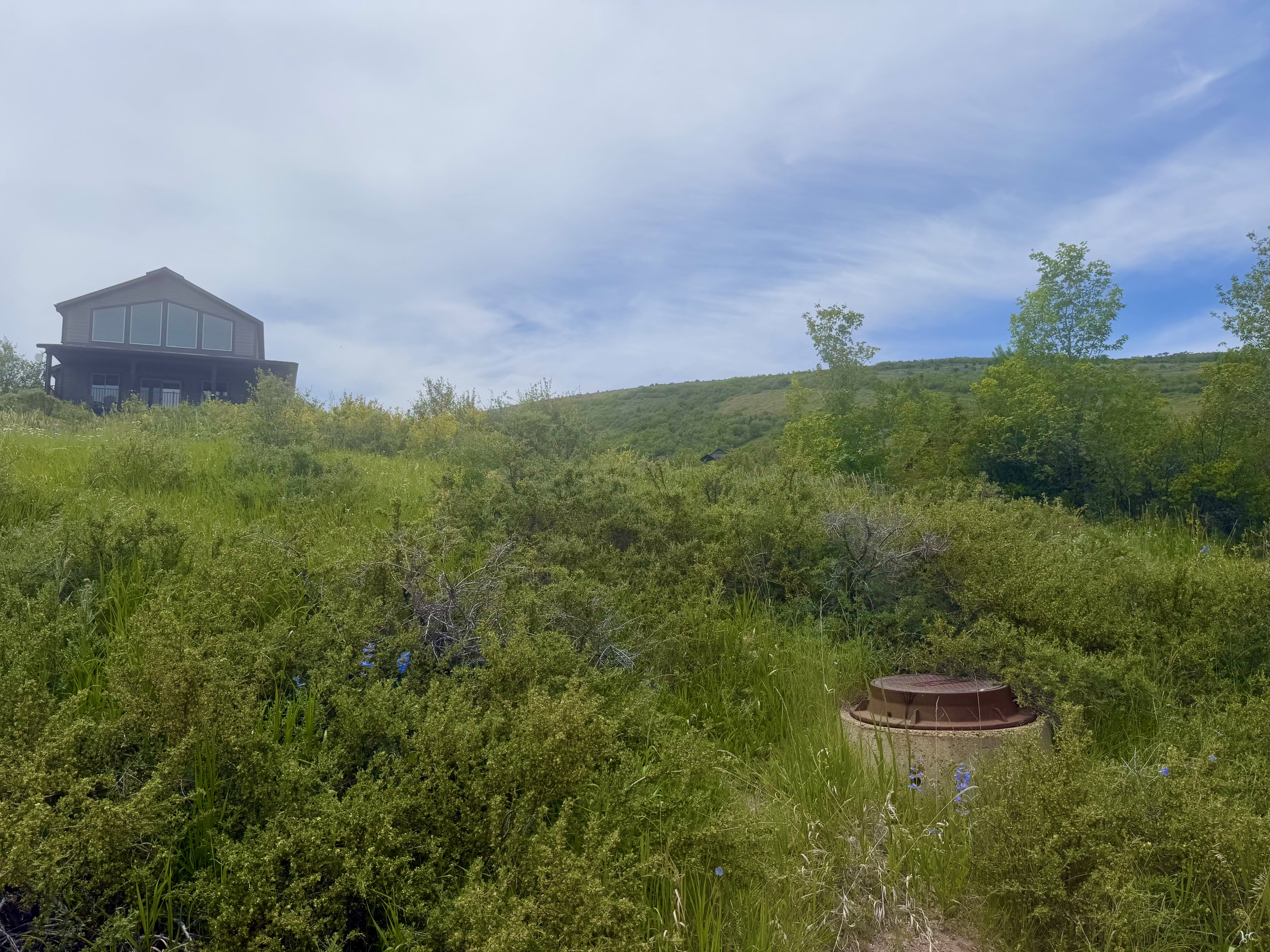 Hillside property with a contemporary-style residence featuring a dark exterior and expansive upper-level windows