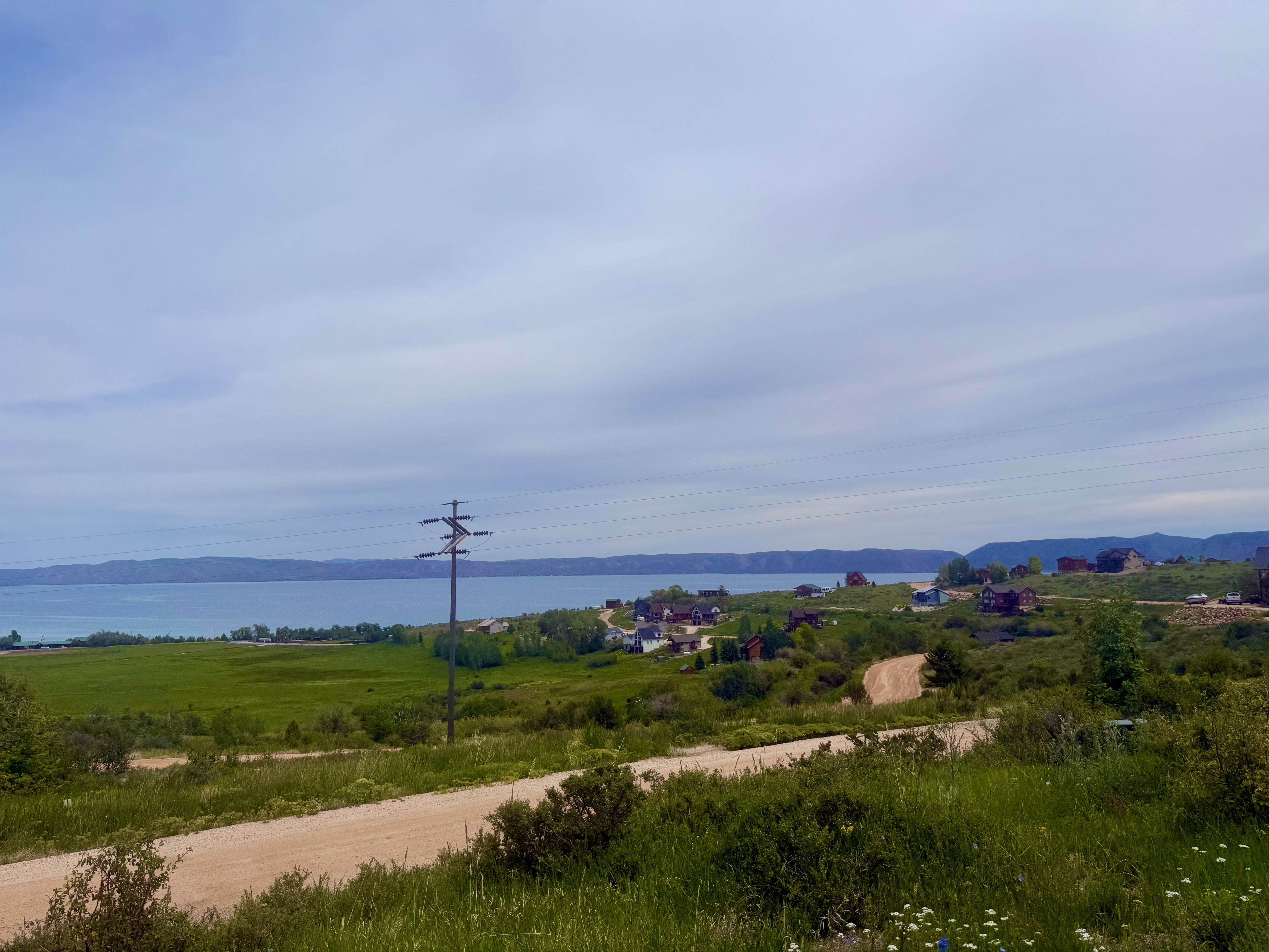 Expansive water body framed by distant hills and a lush green foreground