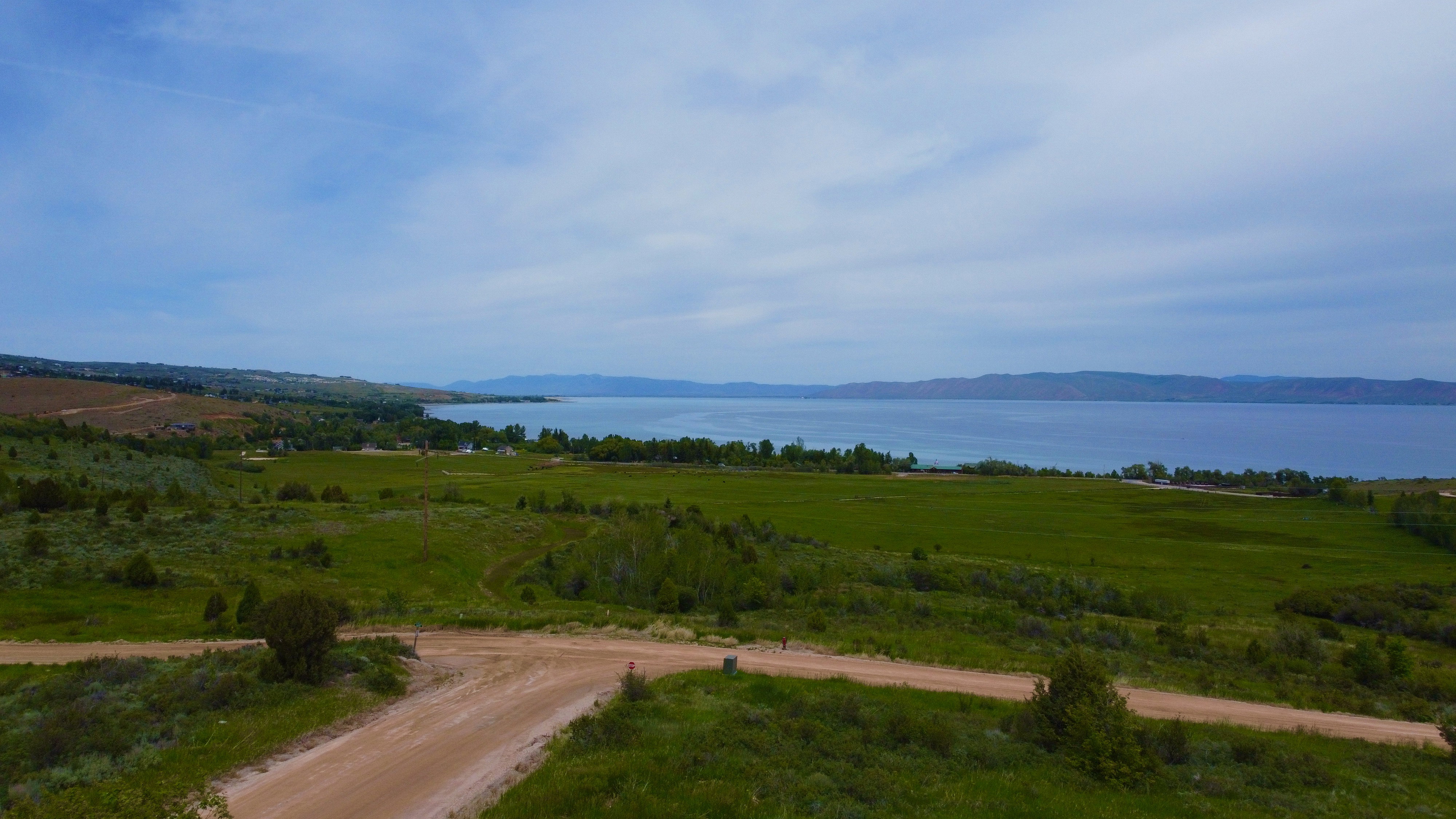 Expansive water frontage property featuring green fields, distant mountains, and a clear water body