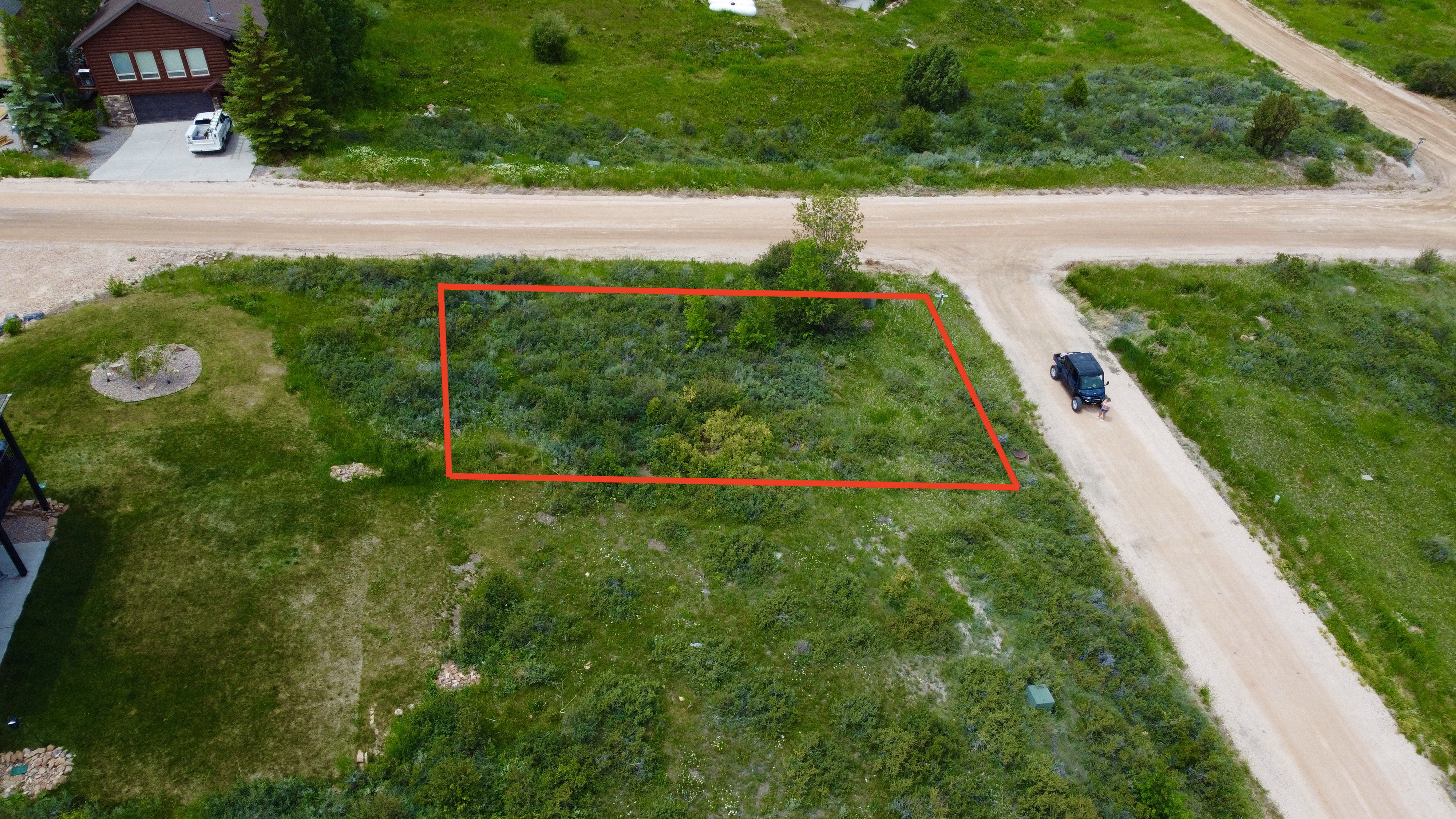 Grassy parcel with a small tree, bordered by unpaved roads