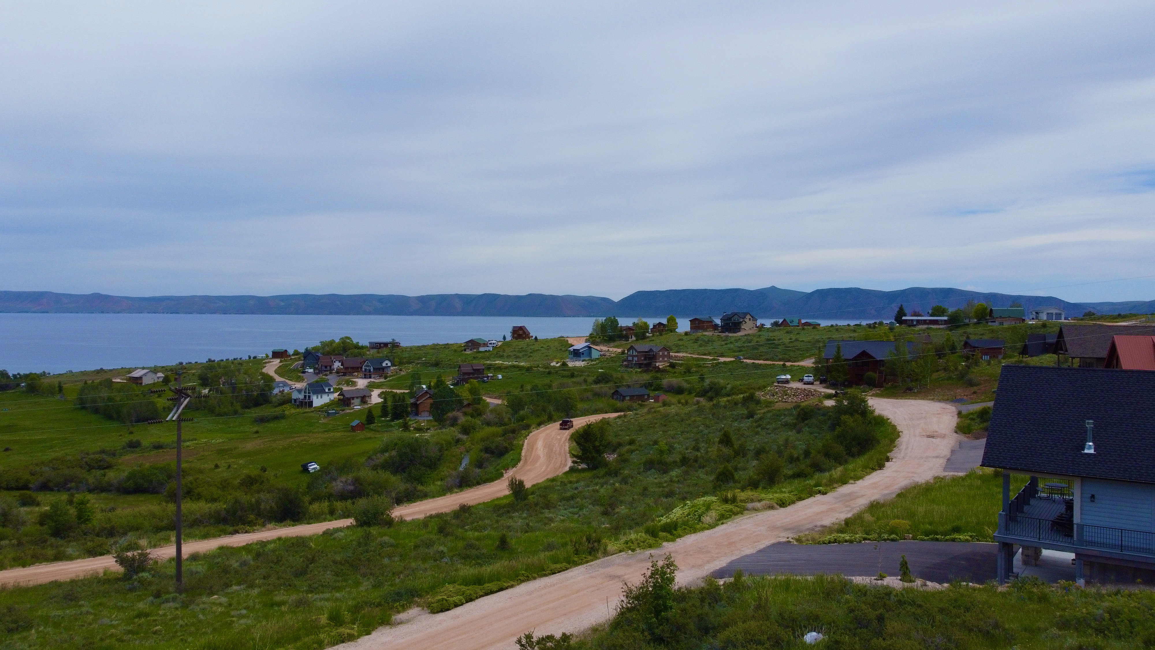 Expansive property featuring a gravel road, lush green landscaping, and distant water frontage