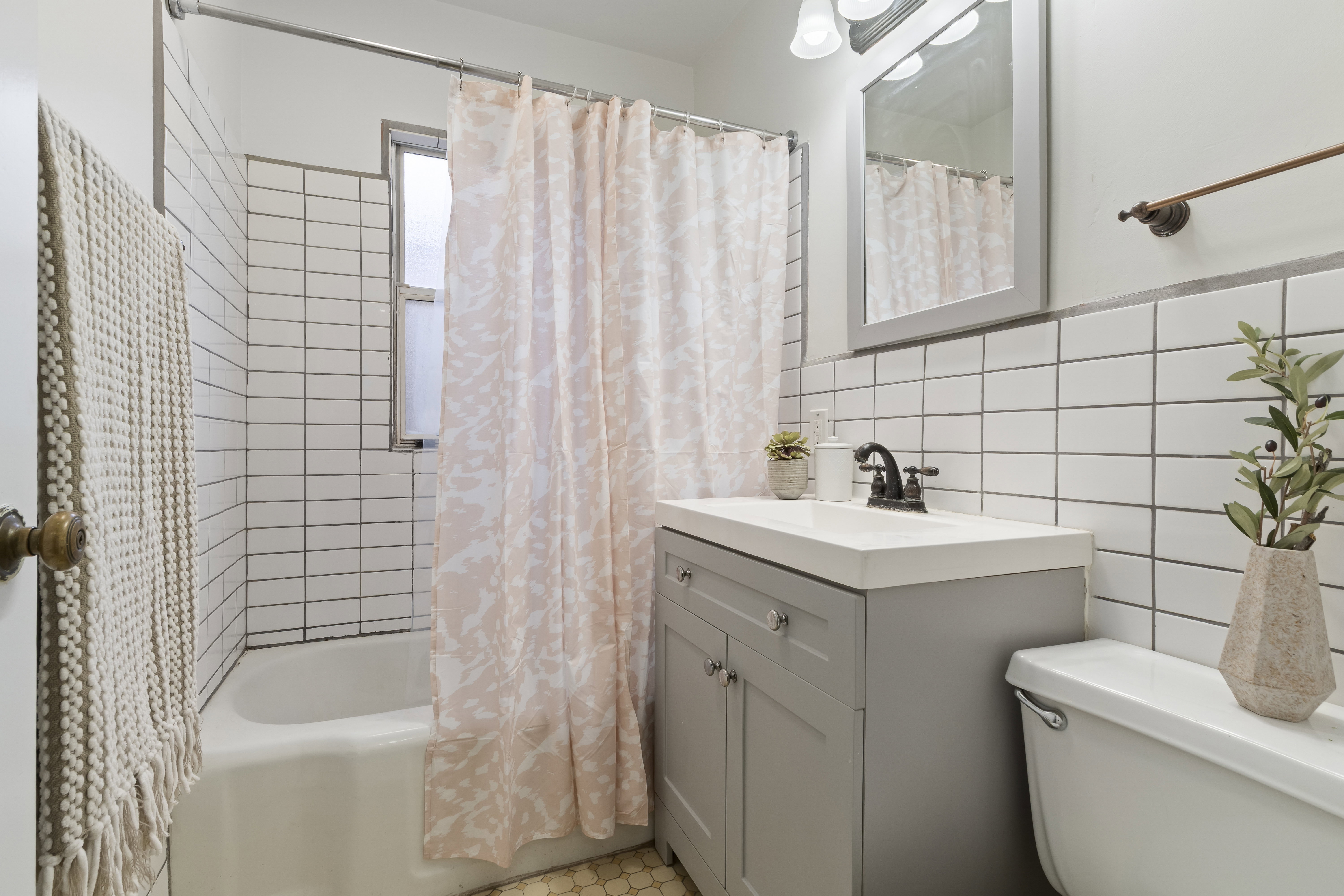 Bathroom featuring a white subway tile surround, white bathtub, gray vanity with integrated sink, and hexagon floor tiling