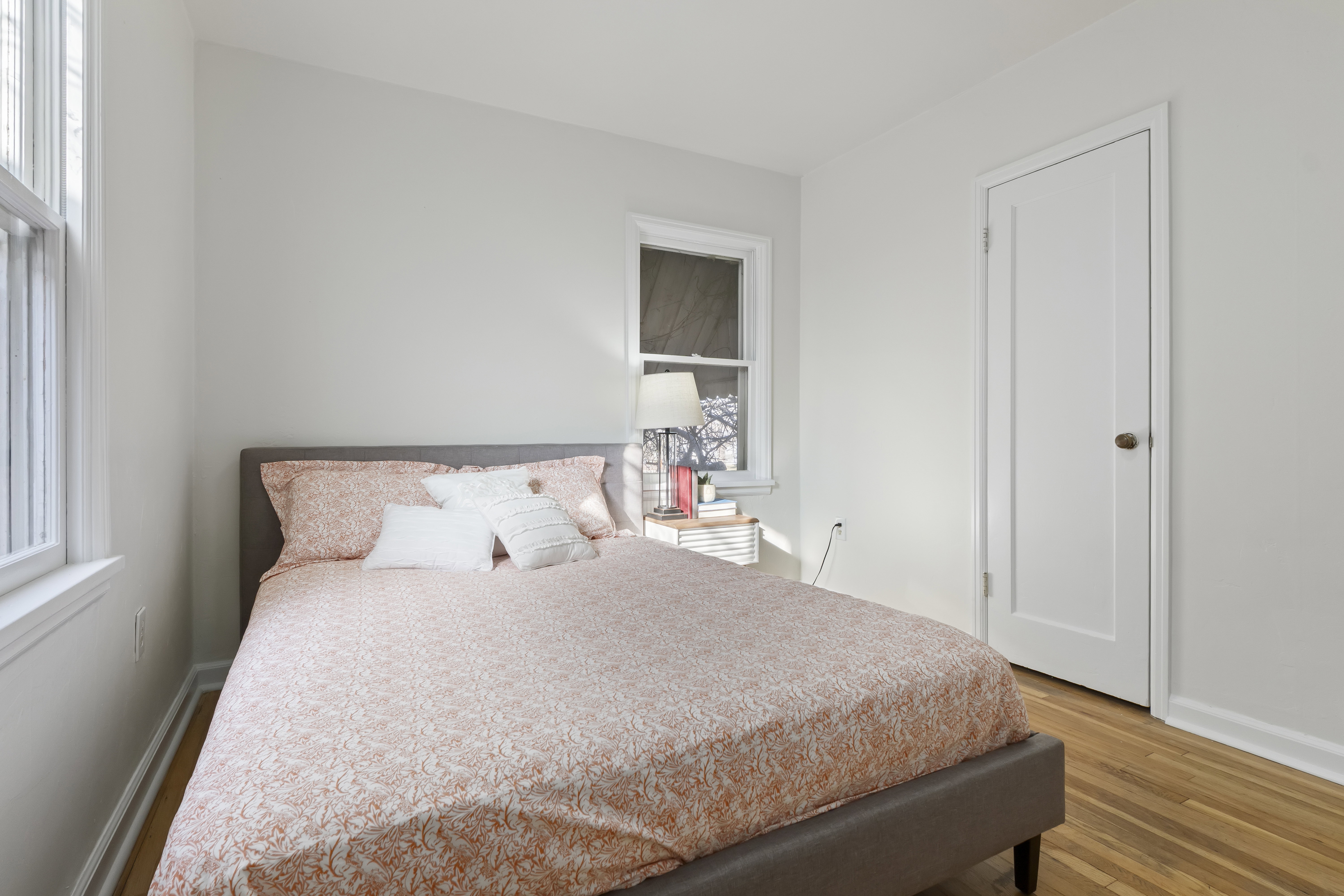 Light-filled room featuring wood-finish flooring, white trim, and a paneled interior door