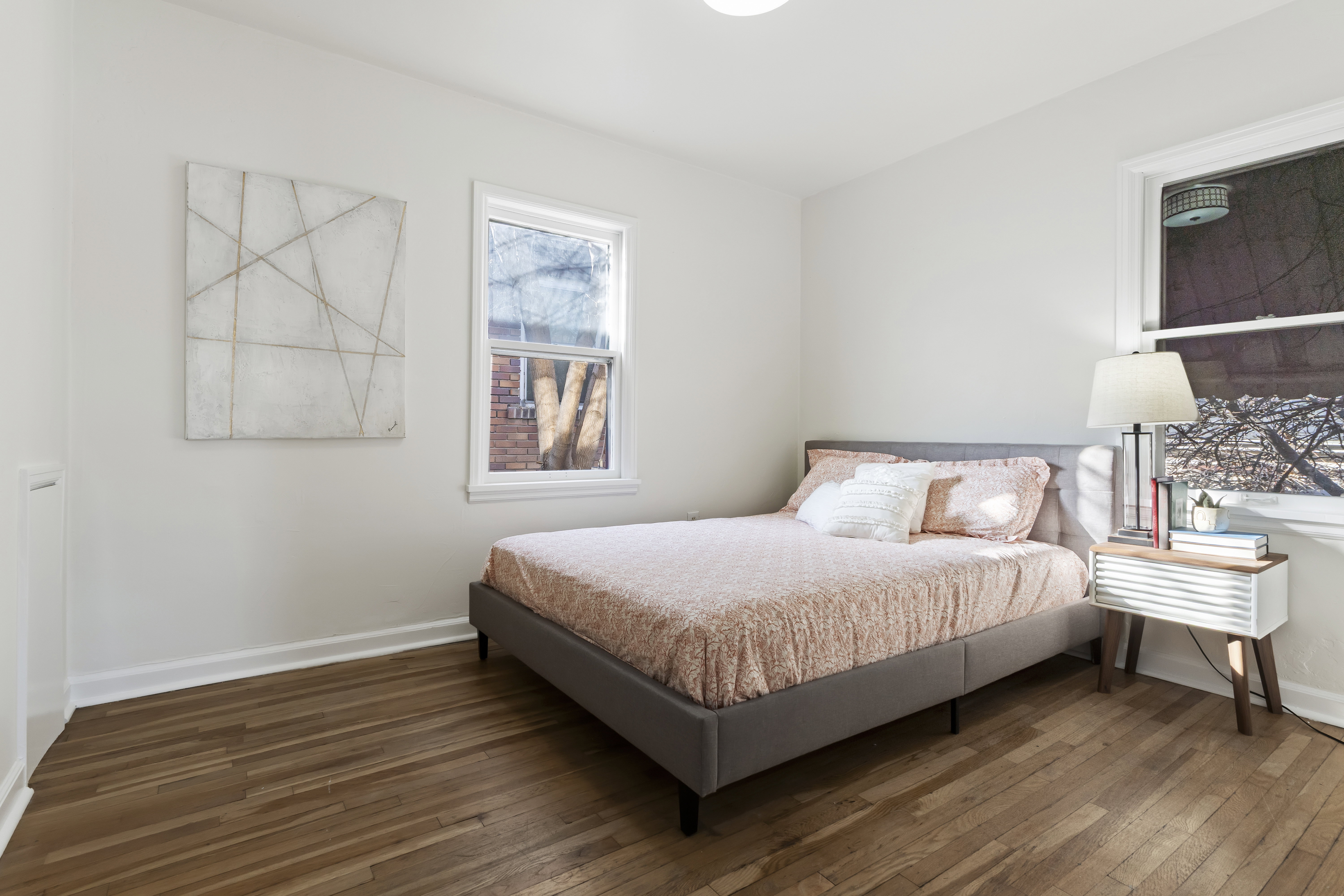 Bright room featuring wood-finish flooring, white baseboards, and two windows with white trim