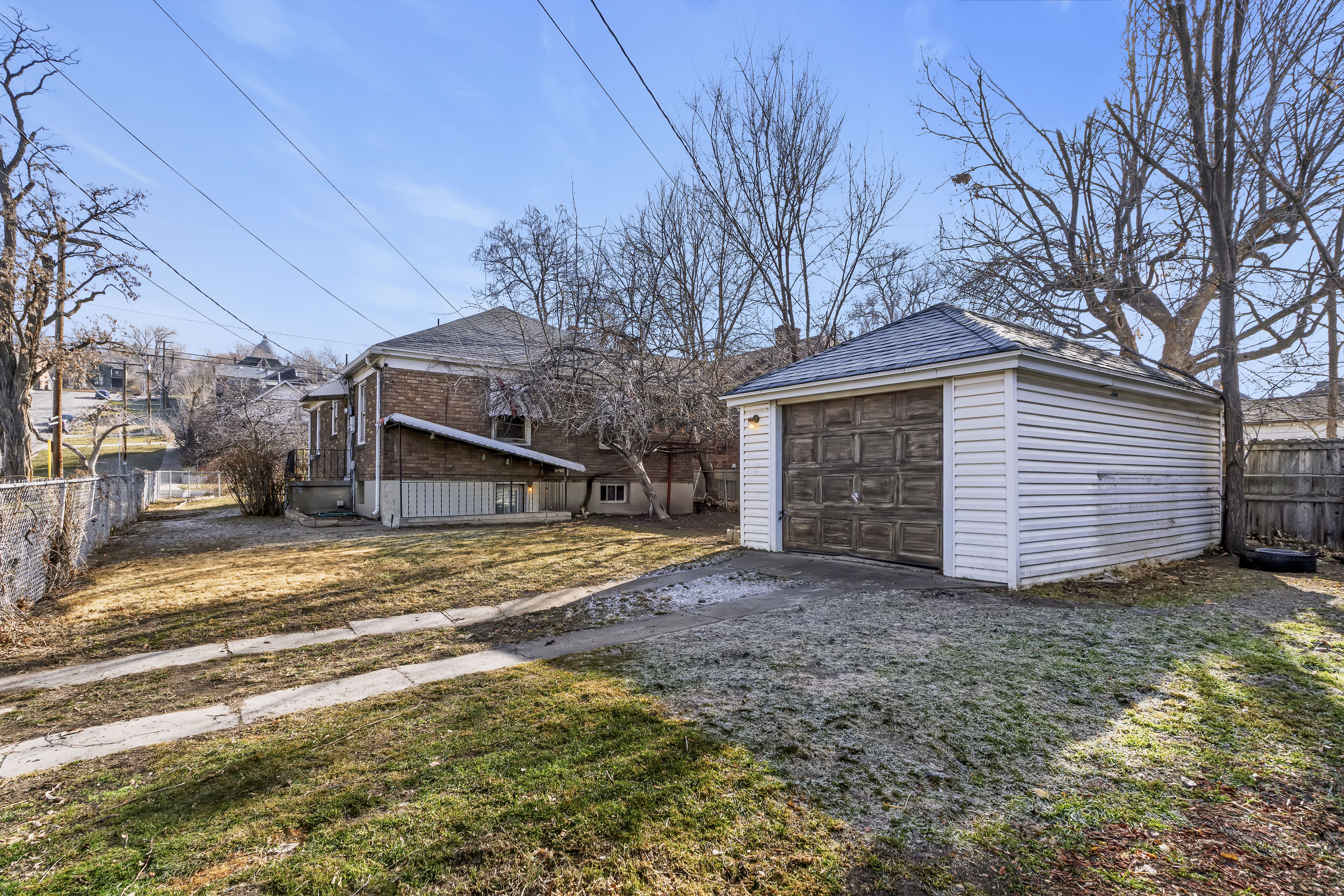 Detached garage with white siding and a weathered wood-panel door