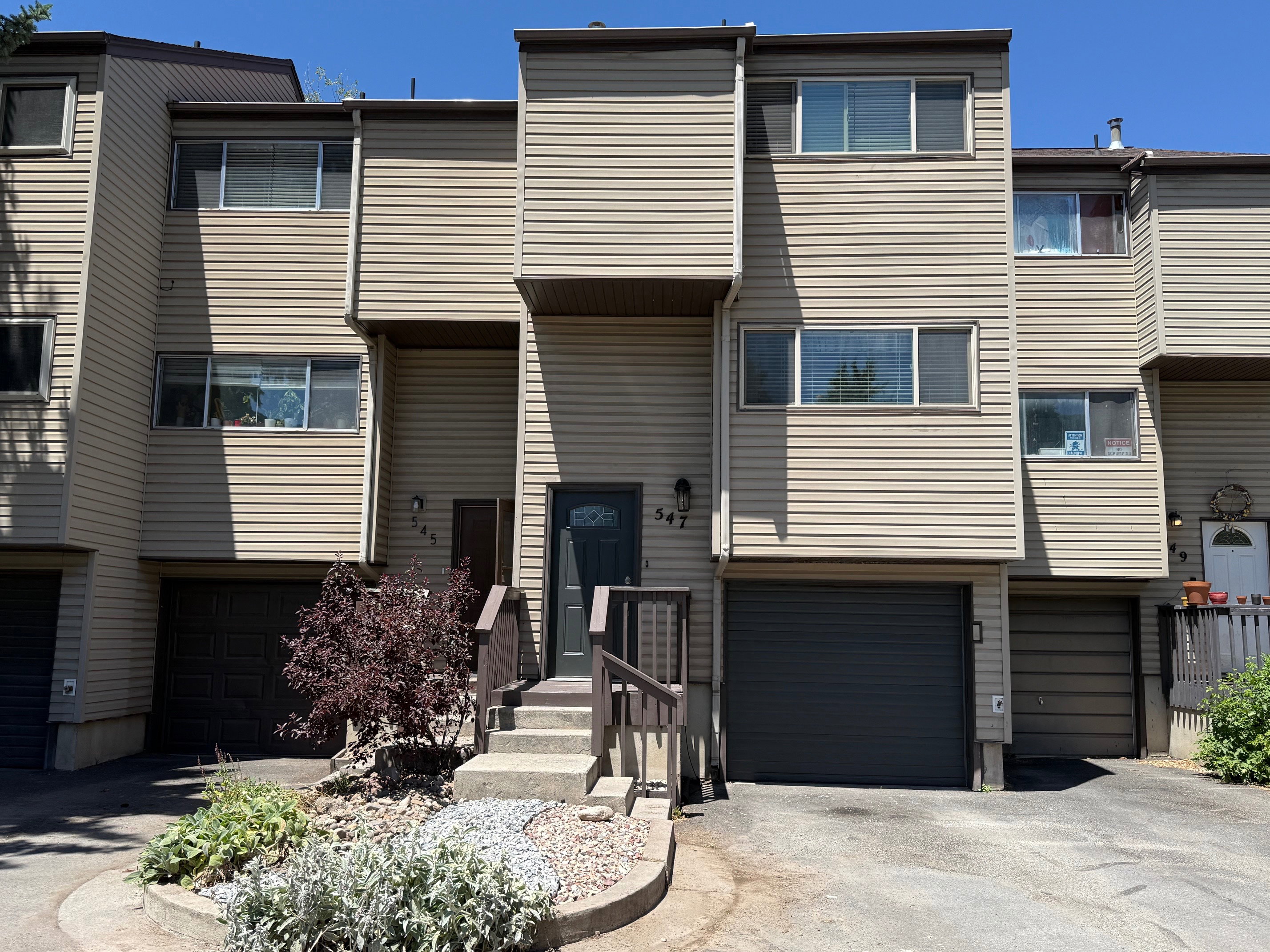 Multi-level townhome exterior featuring neutral siding, multiple windows, and an integrated garage