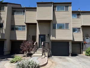 Multi-level townhome exterior featuring neutral siding, multiple windows, and an integrated garage