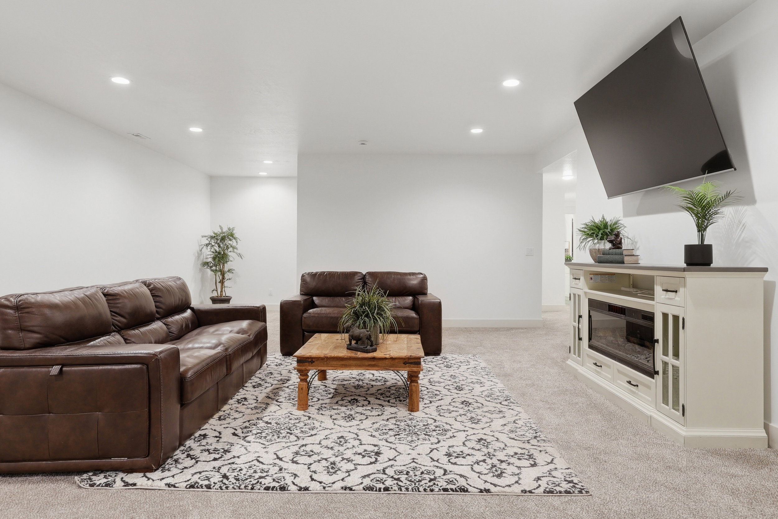 Spacious living area featuring neutral carpeting, recessed lighting, and a built-in media console with an integrated electric fireplace