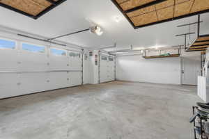 Spacious garage featuring two overhead doors with transom windows, a concrete floor, and ample overhead storage shelving