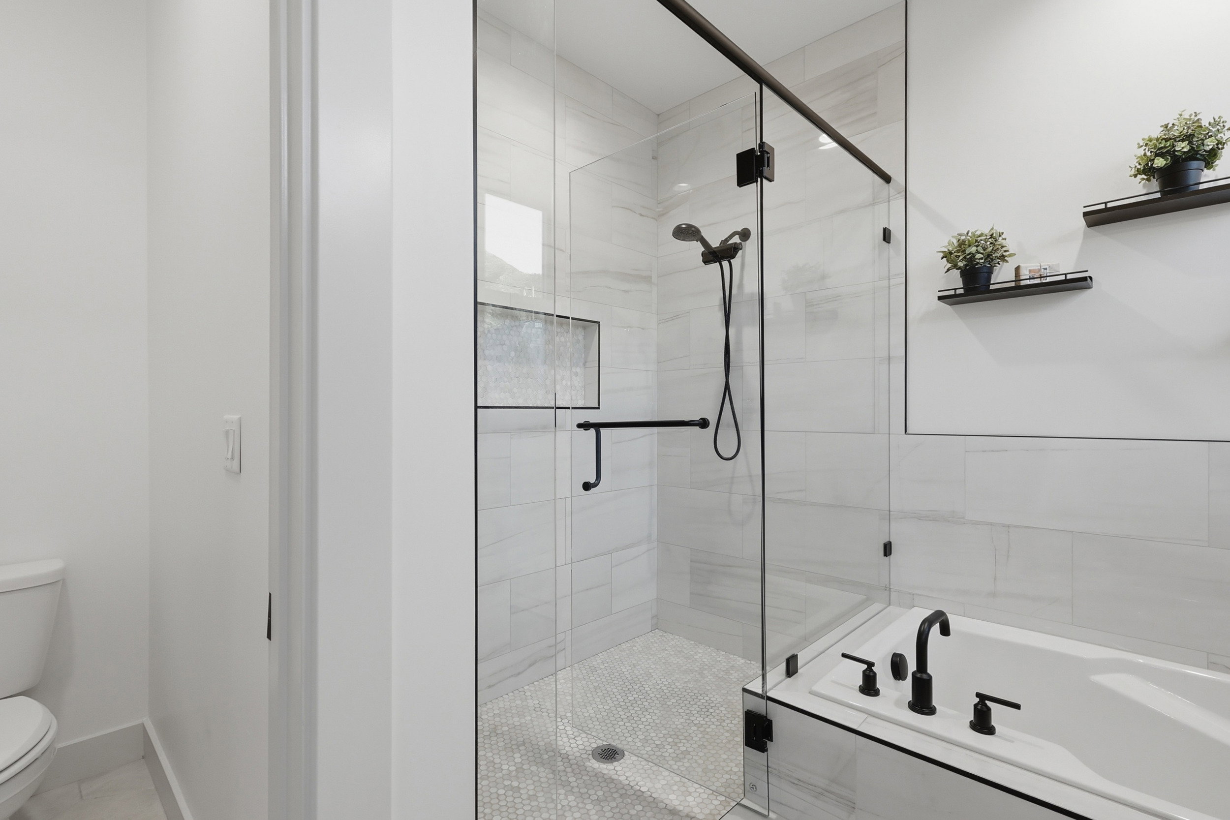 Primary Modern bathroom featuring a glass-enclosed shower with black hardware, a recessed shower niche, and mosaic tile flooring