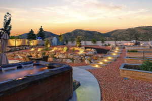 Outdoor spa area featuring concrete patio, tiered landscaping with stone accents, and integrated step lighting