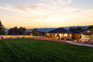 Expansive backyard featuring a manicured lawn, a concrete pathway, and a gravel-bordered landscape with mature trees