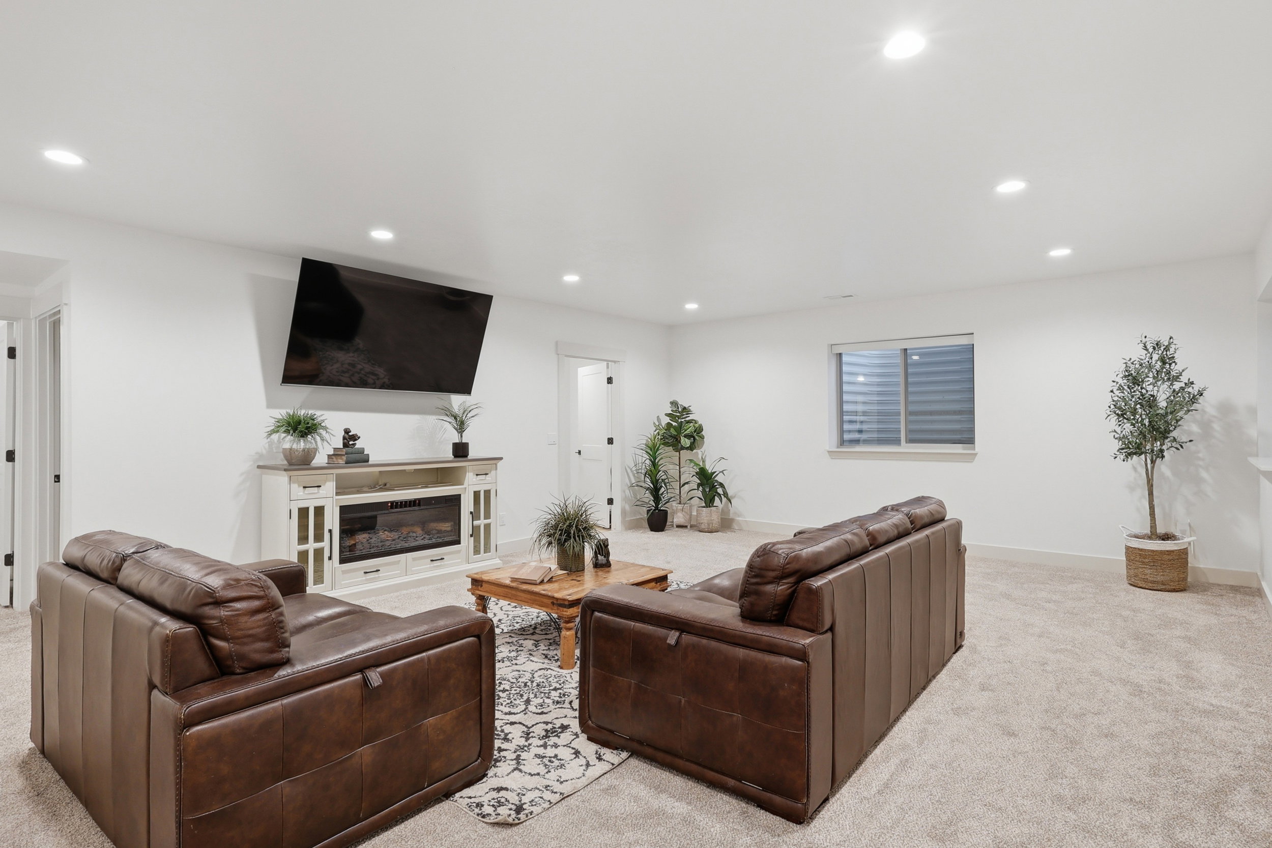 Spacious room featuring light-colored carpeting, recessed lighting, and a window with horizontal blinds