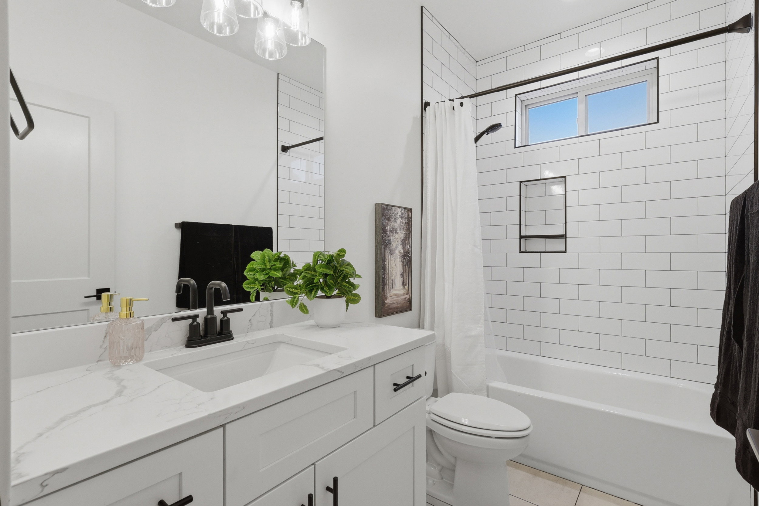 Modern bathroom featuring a single vanity with a white countertop and undermount sink, black-finish faucet, and a large mirror