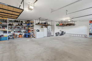 Spacious garage with concrete flooring, overhead storage racks, integrated shelving, and ceiling-mounted lighting